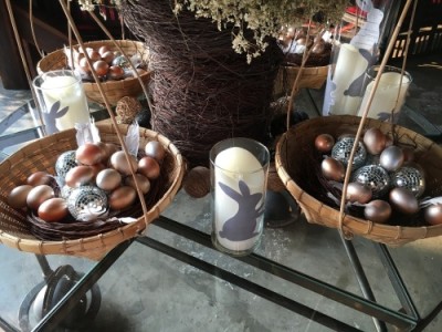 A veľmi avantgardná je stolná výzdoba s prútenými košíčkami s vajcami, prútenými a metalickými loptičkami, doplnené prútenou vázou a pohármi s emblémom zajačikov.